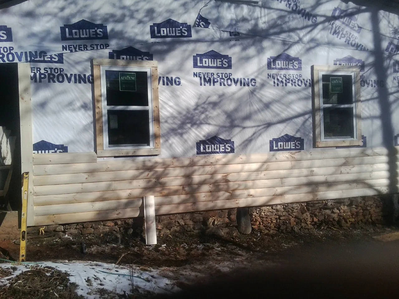 House wrap and new log siding going up on an exterior wall in Silver Springs