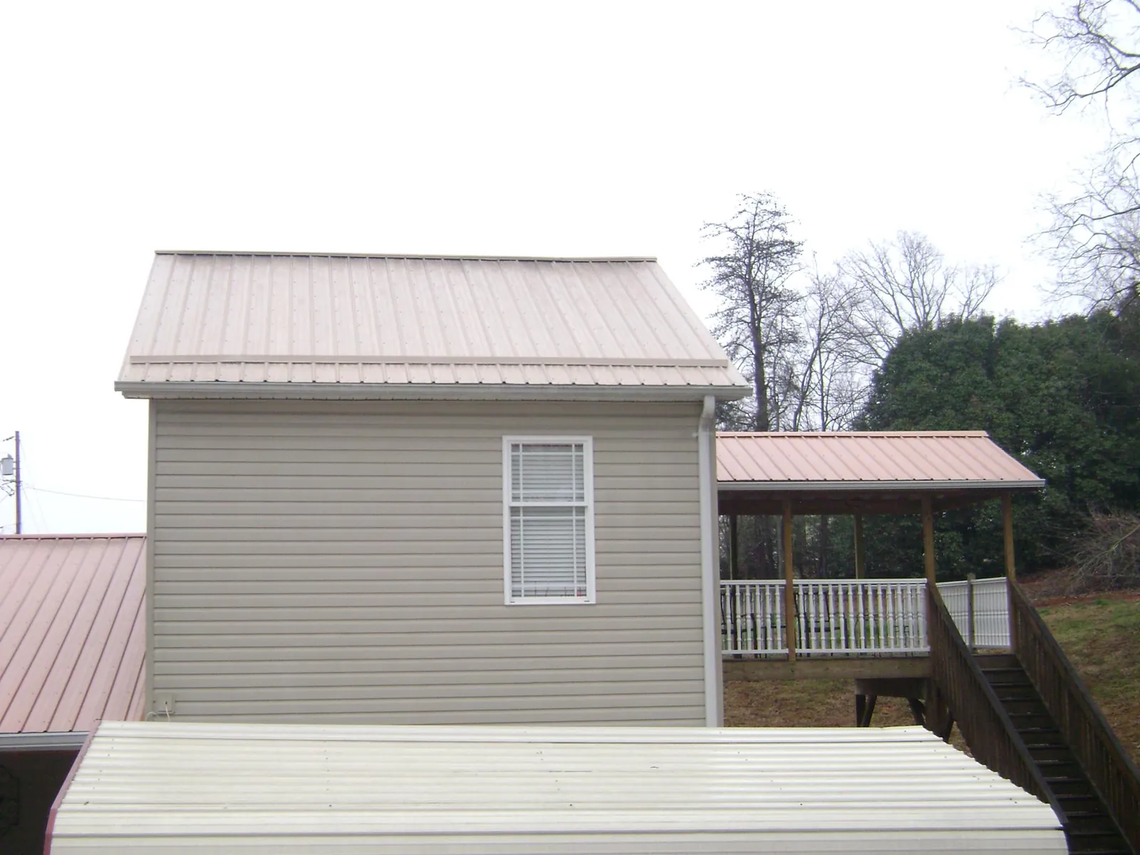 Tan metal roofs on a two story addition and attached porch, from a Roof Replacement job in Silver Springs
