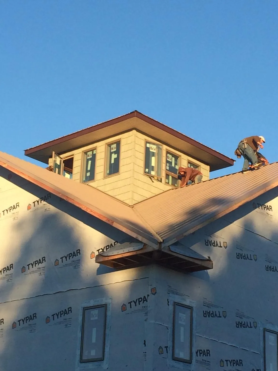 Roofers working around a rooftop cupola on a new metal roof at sunset — Roof Waterproofing in Silver Springs by Roofing Brothers